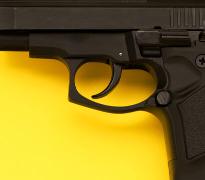 Metal trigger pistol on yellow background, top view