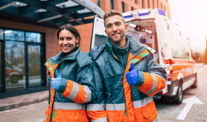 Two confident young doctors looking on the camera on ambulance and hospital background © My Ocean studio