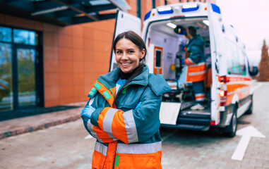 Professional and confident young woman doctor looking on the camera with ambulance background © My Ocean studio