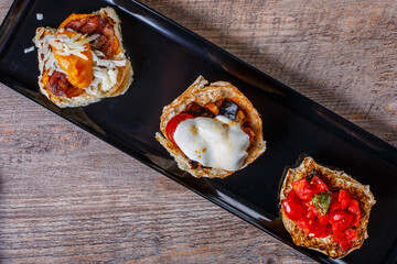 Antipasto con tre bruschette diverse servite su un piatto nero e fotografate dall'alto