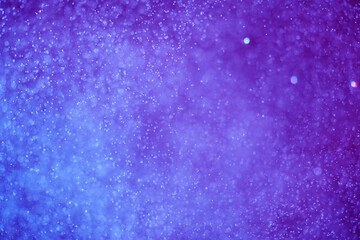 Abstract festive background with selective focus. Bright particles on dark blue background. Splashes, space, energy flow