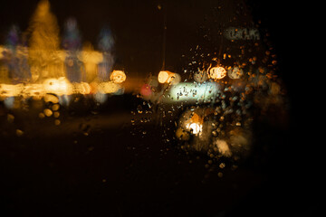 View of the night city through the wet car window with drops