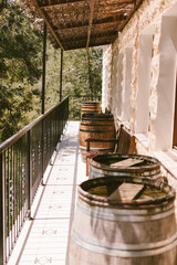 Many wooden barrels along the wall. Wine tasting at the factory, cafe with wine. Terrace with barrel tables.