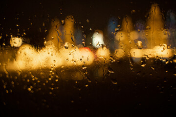 View of the night city through the wet car window with drops