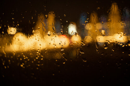 View of the night city through the wet car window with drops