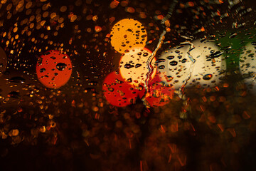 View of the night city through the wet car window with drops