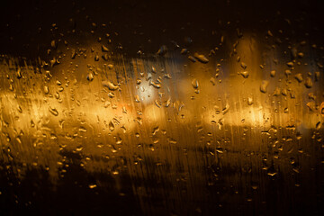 View of the night city through the wet car window with drops