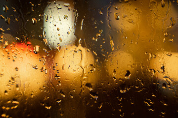 View of the night city through the wet car window with drops