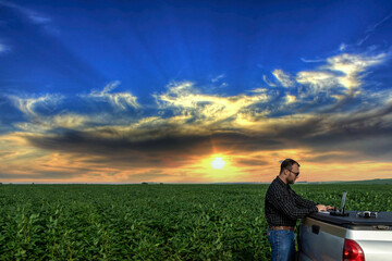 Farmer standing in soybean field looking at notebook and drone