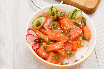 Hawaiian poke with salmon, sesame seeds with wooden cutting board.