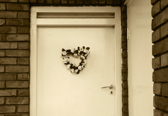 Wedding (or birth) flower wreath in heart shape on door. London, UK. Sepia historic photo.