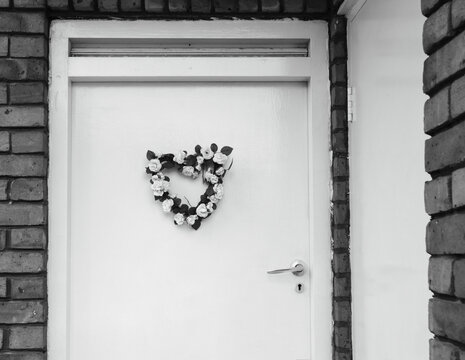 Wedding (or birth) flower wreath in heart shape on door. London, UK. Black and white historic photo.