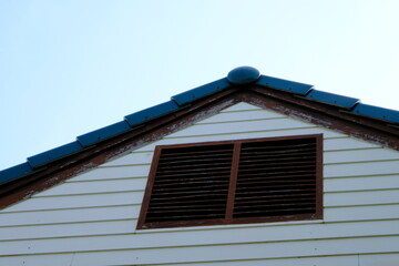 Close up air vent of a house and blue sky.