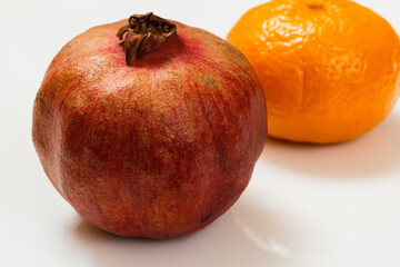 Pomegranate and tangerine on the white background.