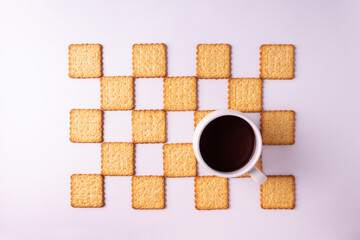 Obraz na płótnie Canvas Background of cookies stacked in a checkerboard pattern on a white surface. A cup of coffee.View from above.