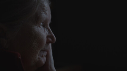 shot of old woman sitting near window dark lit