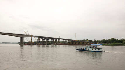 Fototapeta na wymiar Boat floats past with vacationers bridge construction