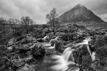 Episches Schwarz-Weiß-Landschaftsbild des Wasserfalls Buachaille Etive Mor im schottischen Hochland an einem Wintermorgen mit langer Belichtung für glatt fließendes Wasser