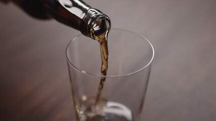 pour cola into tumbler glass on walnut table with copy space