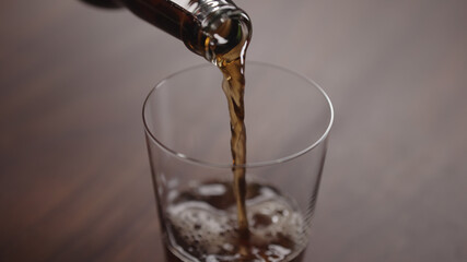 pour cola into tumbler glass on walnut table with copy space