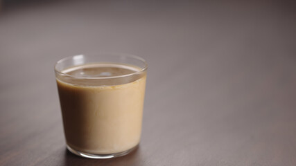 milk pour into tumbler glass with coffee on walnut table