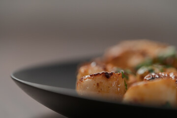 Seared scallops on black plate closeup