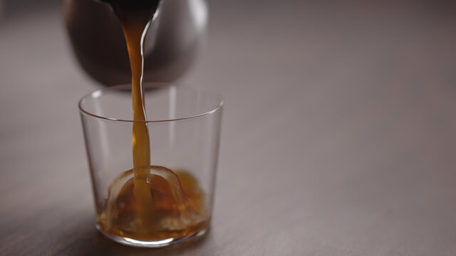 coffee pour into tumbler glass on walnut table