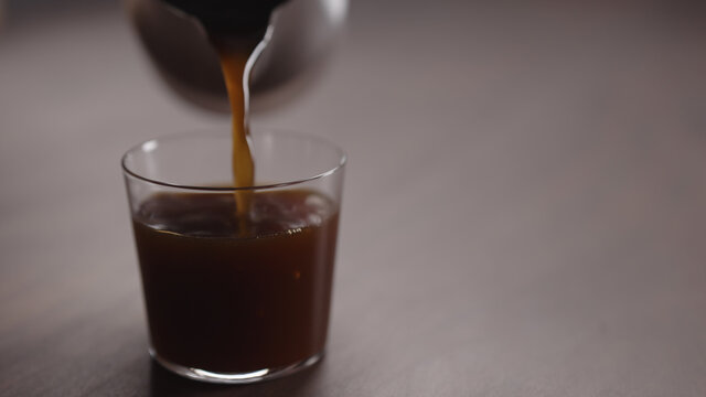 coffee pour into tumbler glass on walnut table