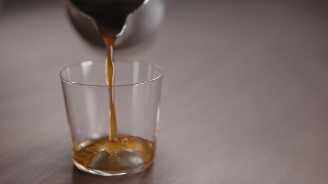 coffee pour into tumbler glass on walnut table