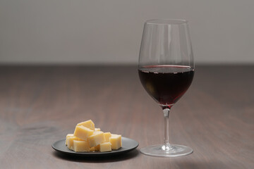 glass of red wine with vintage cheese on small plate