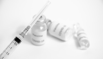 Selective focus on syringe on blurred background of ampoules with vaccine COVID-19. Health protection. Black and white Coronavirus Vaccine with copy space. Vaccination against Sars-CoV-2.