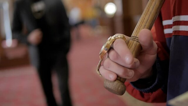 Close-up of the criminal's hands holding a baseball bat and a large amount of cash