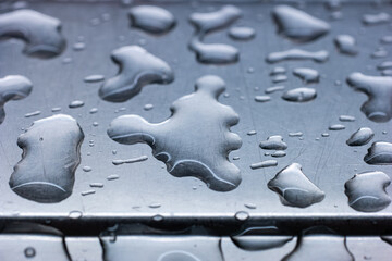 Large water droplets accumulated on blue tint stainless metal sink macro close up shot