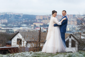 Fototapeta premium two newlyweds on a wedding walk in winter, lovers happily hug and gently kiss, two adults on a date