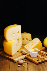 Cheese on table on the dark background. Medium hard cheese head edam, gouda, parmesan on wooden board. Healthy eating concept.