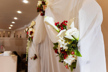 decorations with flowers at the wedding, the interior of the restaurant is prepared by the decorator for the holiday, beautiful fresh flowers in vases on the table, a bouquet as a gift from the guests