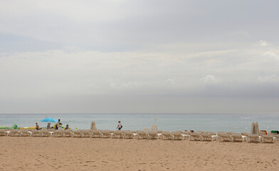 Fototapeta na wymiar Tourists walking and sunbathing on the beach