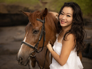 Portrait of smiling woman and brown horse. Asian woman hugging horse. Romantic concept. Love to animals. Nature concept. Bali