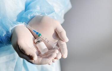 Ampoule with a vaccine and a syringe in the hands of a doctor. Anti-infection concept. Coronavirus...