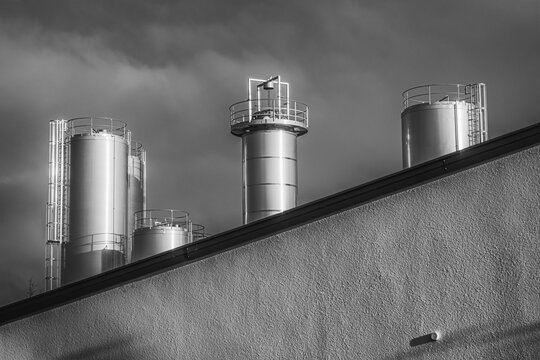 Runde silberne Türme einer Fabrik in schwarz-weiß