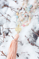Naklejka premium Brass metal spiritual symbol of yantra faceted morganite mala necklace on the white snow