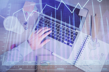 Double exposure of man's hands typing over computer keyboard and forex graph hologram drawing. Top view. Financial markets concept.