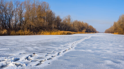 winter frozen river with human track on the snow, winter hiking landscape