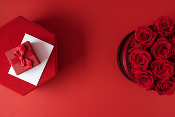 Red roses, red gift boxes and white card on red background
