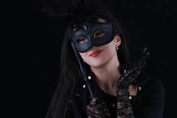 mysterious beautiful girl in a black venetian mask on a black background