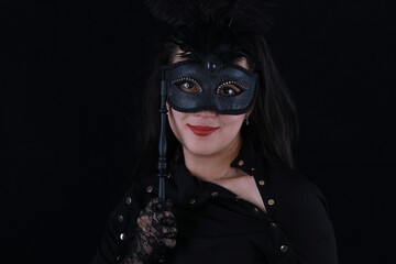studio portrait of a beautiful girl with a theatrical mask on a black background