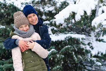 Obraz premium teens portrait in a winter forest, boy and girl, beautiful nature with bright snowy fir trees