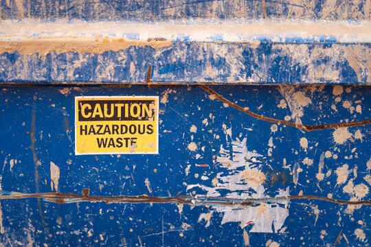 A sticker sign of "Caution, Hazardous waste" on the metal tank which is use for storage chemical waste in the oil drilling industrial.