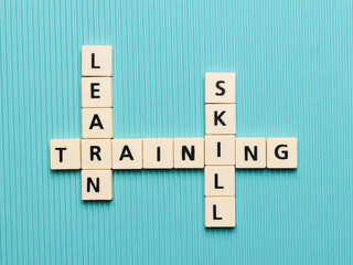 LEARN TRAINING SKILL crossword made from square letter tiles on turquoise background.Business concept.