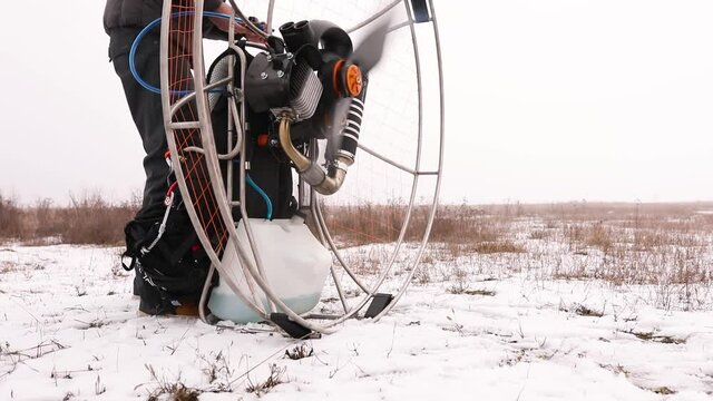 Close up of man hands starts to work a propeller, motor, engine of the paramotor paraglider